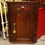 A George III oak hanging corner cabinet, with single panelled door