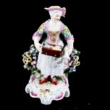 A 19th century porcelain figure, woman selling trinkets, height 15cm