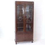 A 1920s oak bookcase, with 2 leadlight glazed doors, and cupboards under, on bun feet, W86cm,