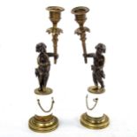 A pair of French bronze and ceramic cherub design candle holders, height 30cm