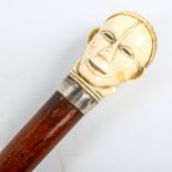A malacca walking cane with African carved ivory head design handle, Continental silver collar,