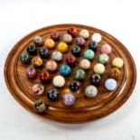 A set of agate and hardstone marbles on turned wood solitaire board, diameter 36cm, marbles diameter