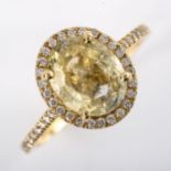 A modern 14ct gold yellow sapphire and diamond halo cluster ring, set with oval mixed-cut sapphire