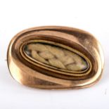 A small Georgian unmarked gold mourning brooch, central oval woven hair panel under convex glass