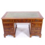A reproduction yew wood twin-pedestal writing desk, with a tooled green leather skiver and fitted