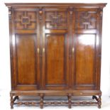 A 1920s panelled oak 3-door wardrobe, on a baluster turned base, L190cm, H207cm, D60cm