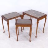 A walnut nest of 3 occasional tables, with glass tops, widest 55cm