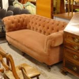 A Victorian button-back upholstered rollover arm Chesterfield settee, raised on 6 mahogany turned