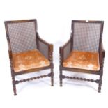 A pair of 1920s oak-framed bergere armchairs, with loose cushions (1 chair slightly shorter than the