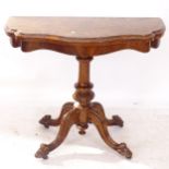 A Victorian walnut fold over card table of serpentine form, on a turned centre column and sabre