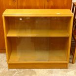 A 1920s light oak bookcase of tapered form, with sliding glazed doors, W92cm, H84cm, D34cm