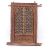 An ornate Indian hardwood and brass decorated window, with allover relief carved decoration,