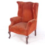 An Antique upholstered fireside wing armchair, on walnut cabriole legs