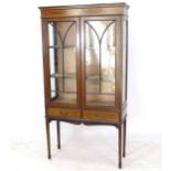 An Edwardian mahogany and satinwood-strung display cabinet, with lattice-glazed doors, and drawers