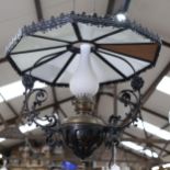 A wrought-iron framed brass ceiling oil lamp, with milk glass panels and milk glass chimney, overall