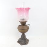 A Veritas brass oil lamp, with cast-iron base, fluted cranberry glass shade and clear glass