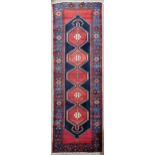 A red ground Afghan wool runner, 303cm x 105cm No holes or tears, some slight fading and staining to