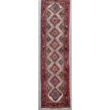 An Iranian red ground Hamadam wool runner, geometric design, 300cm x 84cm No holes or tears, colours