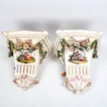 A pair of French porcelain wall shelf brackets, with painted romantic scenes and applied swags of