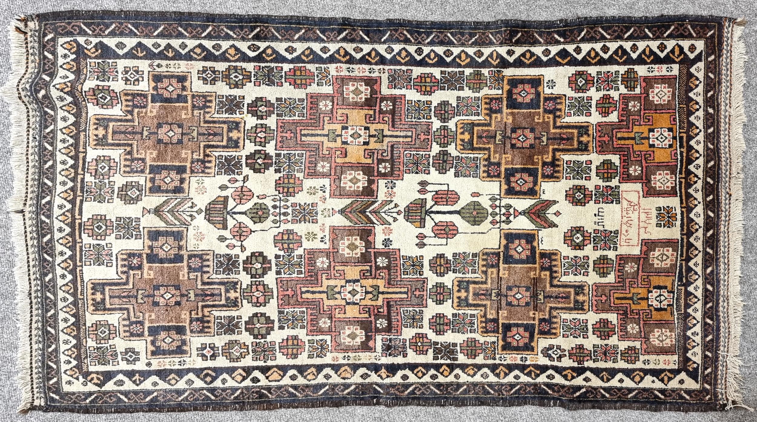 An Antique handmade Afghan wool rug, geometric floral design with Arabic script, 205cm x 121cm