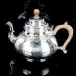A George V silver squat teapot, in Queen Anne style, with scrolled spout, planished finish and
