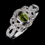 A modern peridot and diamond dress ring, unmarked white metal settings with oval mixed-cut