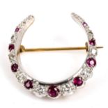 A late 20th century 9ct gold ruby and diamond crescent brooch, set with round cut gemstones, total
