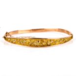 An early 20th century 9ct gold hollow hinged bangle/bracelet, relief embossed foliate decoration,