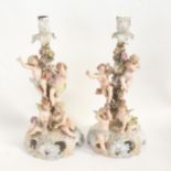 A pair of Continental porcelain candlesticks, supported by cherubs and garlands of flower, height