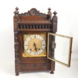 A 19th century carved walnut-cased 8-day mantel clock, with brass dial and striking movement, height