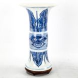 A Chinese blue and white porcelain cylinder vase with flared rim dragon masks, hardwood stand,