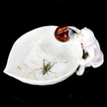 A Japanese Hilrado white glaze porcelain dish in the form of a monkey holding a leaf, with painted