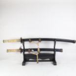 2 Samurai style swords with composition hilts, on fitted display stand, longest 90cm