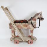 A push-along painted wooden horse on wheels, height 66cm