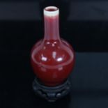 A small Chinese sang de boeuf bottle vase, height 12cm, on hardwood stand