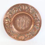 An Arts and Crafts copper church communion plate, relief embossed heart and grapevine border,
