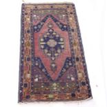 A red ground Persian design rug, with symmetrical border and central panel, 206cm x 114cm