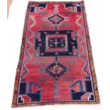 A red ground Afghan rug, abstract symmetrical decoration, 215cm x 114cm