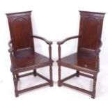 A pair of Gothic design panelled oak bow-arm hall chairs, on turned legs