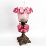 A Victorian oil lamp with faceted cranberry glass font, on cast-iron base, frilled cranberry