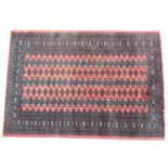 Turkman Bokhara woollen rug, madder field with three rows of guls within a wide guardstripe