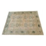 Indian gold ground woollen carpet, detailed with a formalised grid pattern of green and ochre