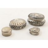 Four silver pill boxes, including a repousse oval example, Chester 1897, 6cm; another oval box