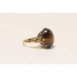 Tiger's eye dress ring in 9ct gold, the cabochon stone approx. 16mm, in a claw mount with leaf