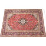 Kashan red ground woollen carpet, centred with a blue and fawn reserve and similar spandrels
