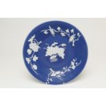 Chinese blue ground dish, 19th Century, slip decorated with white foliate sprays around a lotus