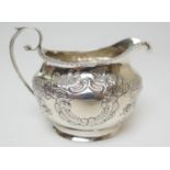 Late Victorian silver milk jug, maker TH, Birmingham 1900, helmet shaped with repousse decoration of