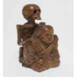 Japanese carved boxwood okimono, formed as a skeleton on the back of a seated man, signed, 7.5cm