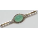 Jade and diamond bar brooch, the celadon green cabochon bordered with rose cut diamonds set in white