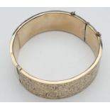 9ct gold hinged bangle, chased with foliate scrolls, with safety chain, interior size approx.